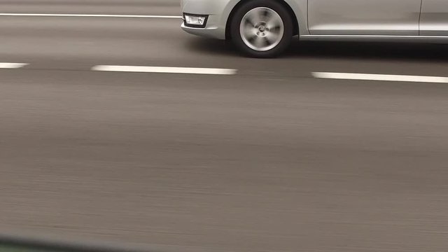 Slow motion shot of the wheels of a car driving along a road.