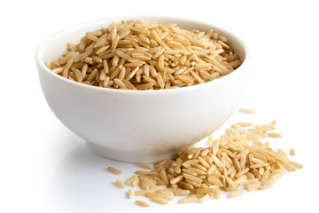 Bowl of long grain brown rice isolated on white. Spilled rice.