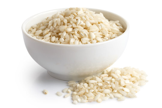 Bowl of Arborio short grain white rice isolated on white. Spilled rice.