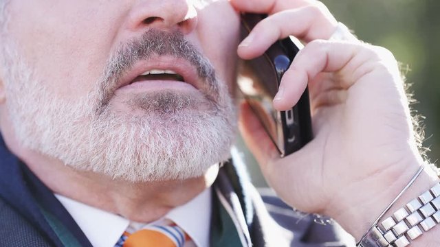 4K Close up of the mouth of a mature business man talking on his phone, in slow motion