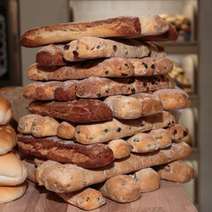 Heap of Bread Rolls Assortment and French Loaf on Wooden Board