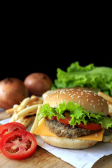 Grilled beef hamburger with vegetables on wood table, over light [blur and select focus background]
