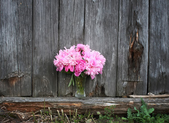 Fototapeta na wymiar Bouquet of peony flowers on the wooden wall background