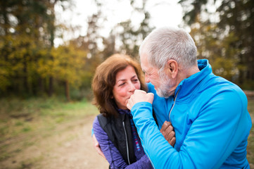 Beautiful senior couple running outside in sunny autumn forest