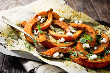 Roasted, baked pumpkin with addition aromatic herbs, goat cheese and mint. Healthy food concept...