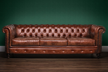 Brown chesterfield sofa with green wallpaper background