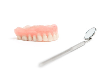 upper dentures and dental mirror on white background