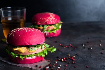 Closeup of homemade burgers with lettuce and sausage on a black wooden background