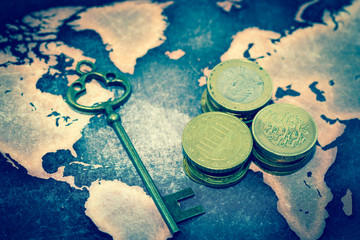 Fototapeta na wymiar Key with pile of coins on grunge world map
