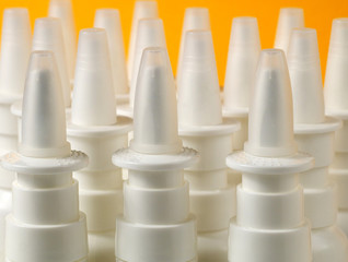 a bulk of nasal spray bottles on orange background, shallow depth of field