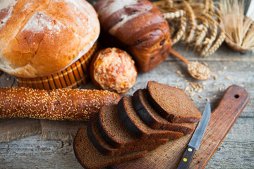 Tasty fresh bread and wheat on the old wooden table