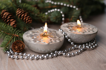 Silver Christmas candles decorated with snowflakes near christmas tree, garlands.  