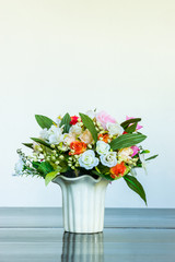 Vase of artificial rose on wooden bench