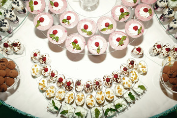Pink yogurt desserts with berries stand on white dinner table