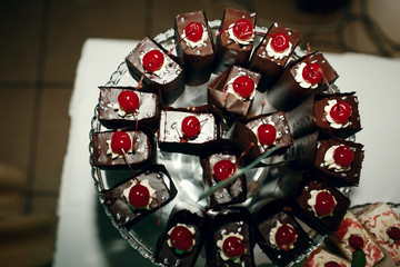 Dark chocolate desserts with cherries stand on the glass dish