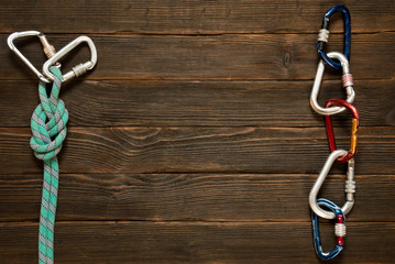 climbing rope and carabiner on dark wooden background, top view.