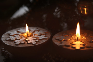 Silver Christmas candles decorated with snowflakes near christmas tree, garlands.  Candlelight.
