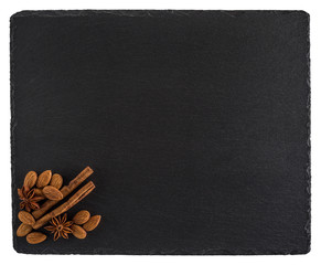 Almonds, cinnamon and star anise on a black slate board. Isolate