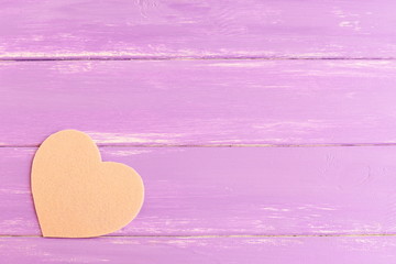 Fototapeta premium Beige felt heart on purple wooden background with blank copy space for text