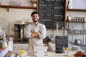 Business owner at the counter of coffee shop, arms crossed - obrazy, fototapety, plakaty