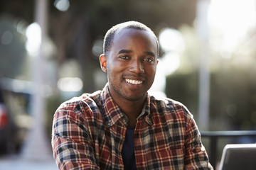 Young black man sitting outdoors, portrait