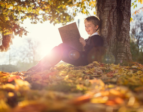 Boy sitting under a tree reading book