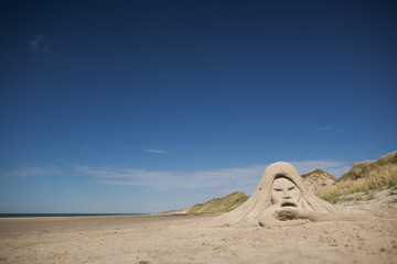 Fototapeta na wymiar Sandskulptur Neptun an wildem Strand