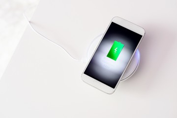 White smartphone charged by wireless charger © Daniel Jędzura