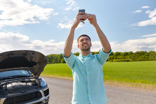 man with smartphone and broken car at countryside