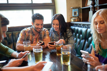 friends with smartphones and beer at bar or pub