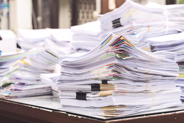 Pile of documents on desk stack up high waiting to be managed