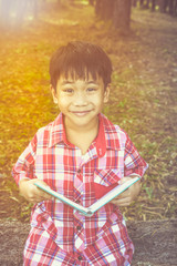 Happy asian boy smiling and holding a book. Education concept. 