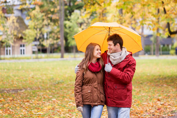 smiling couple with umbrella in autumn park