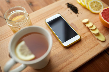smartphone with cup of lemon tea, honey and ginger