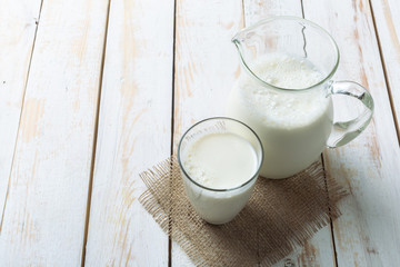 fresh milk in glass jug and glass on wooden background