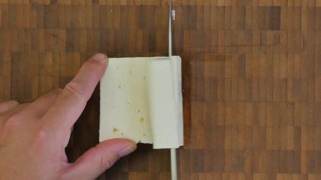 Chopping feta cheese on a rustic wooden table - flat lay 4K