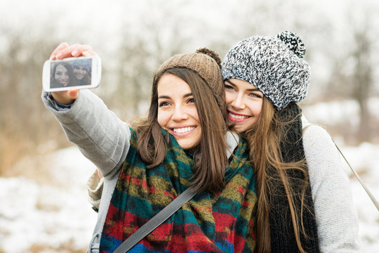 Two teenage girls taking a selfie in winter