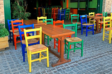 Fototapeta na wymiar greek tavern with wood table and multicolored chairs,Crete, Greece