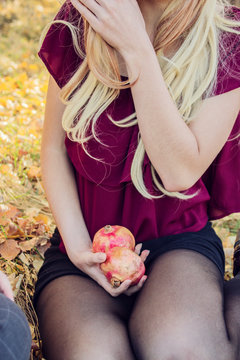 Chica joven con ropa de otoño sosteniendo un par de granadas entre sus manos