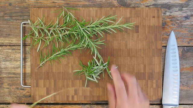 Cutting rosemary on a rustic wooden table - top view 4K