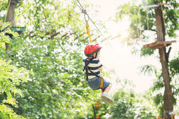 Kids climbing in adventure park. Boy enjoys climbing in the rope