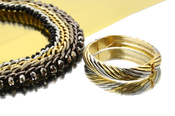 Necklace and bracelet on golden and silver mirror background