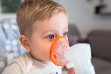 Little boy taking inhalation therapy by the mask of a nebuliser - obrazy, fototapety, plakaty
