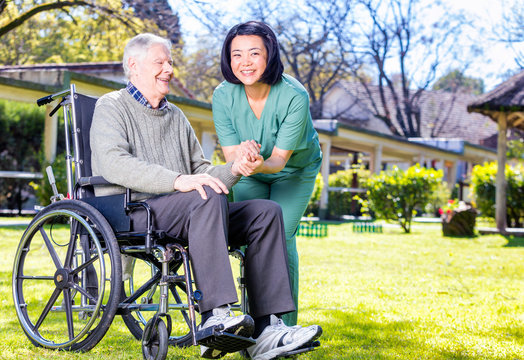 Asian nurse happy with caucasian elder patient on wheelchair, ou