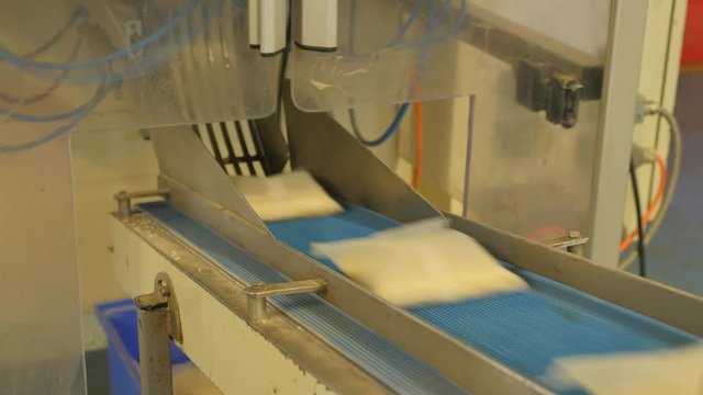 Packed bags of white rice travelling along the assembly line in a factory &ndash; 4K