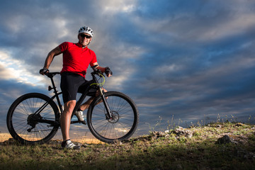 Sportive man with bicycle at sunset