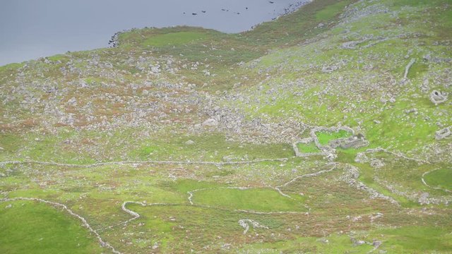 A small lake in the middle of the mountain steep with the green grasses and rocks that can be seen in Skyroad route in Ireland