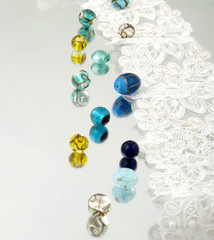 Shimmering glass beads and vintage lace on mirror background 