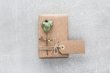 Hand crafted gift with dry autumn branches on rustic gray background. Gift wrapping concept. Flat lay. View from above.
