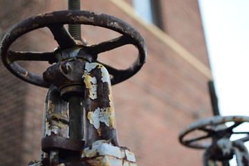 Rusty Pressure Release Valve with Brick Wall in Background 